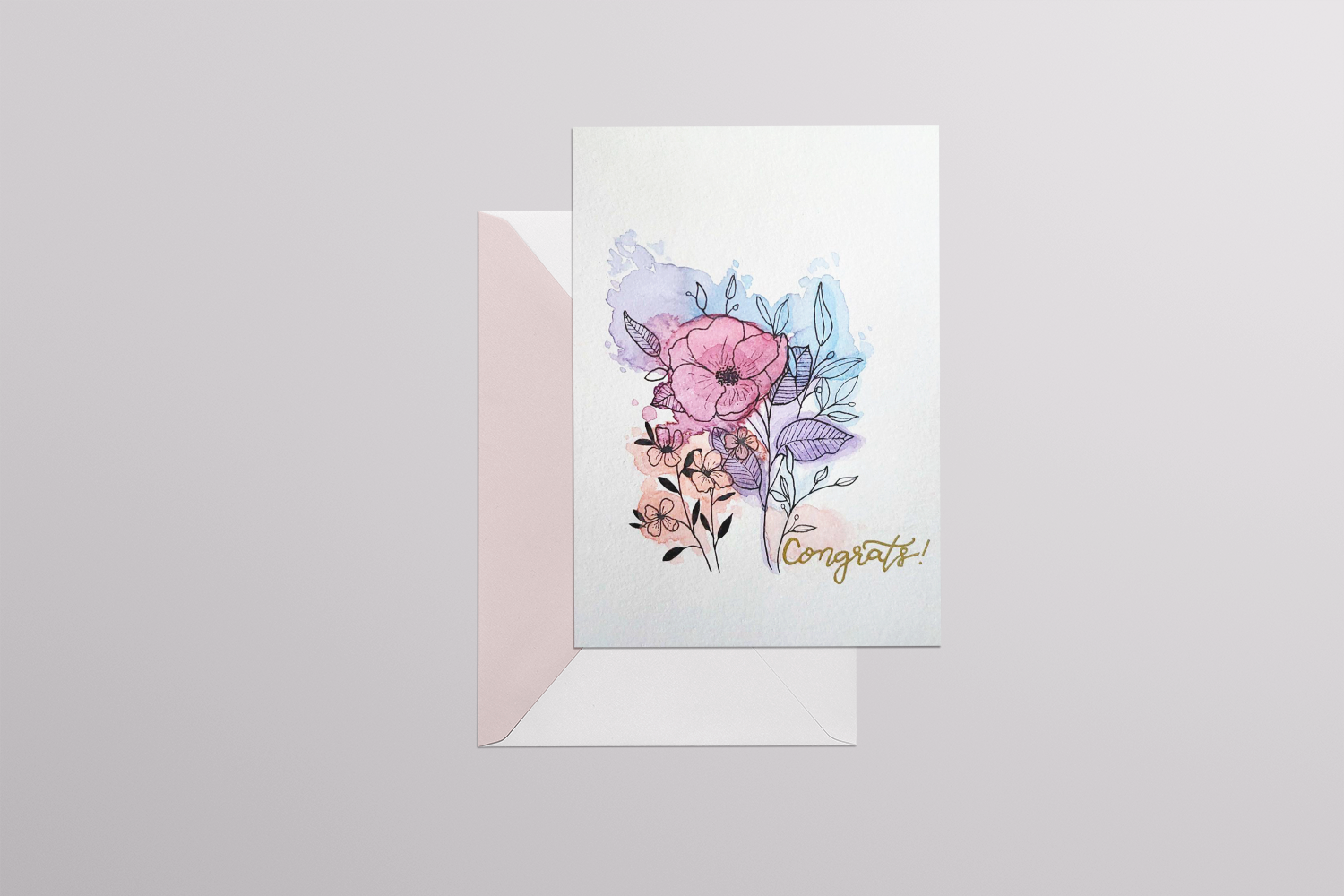 Mockup of card with watercolor florals and handwritten “Congrats!” with envelope
