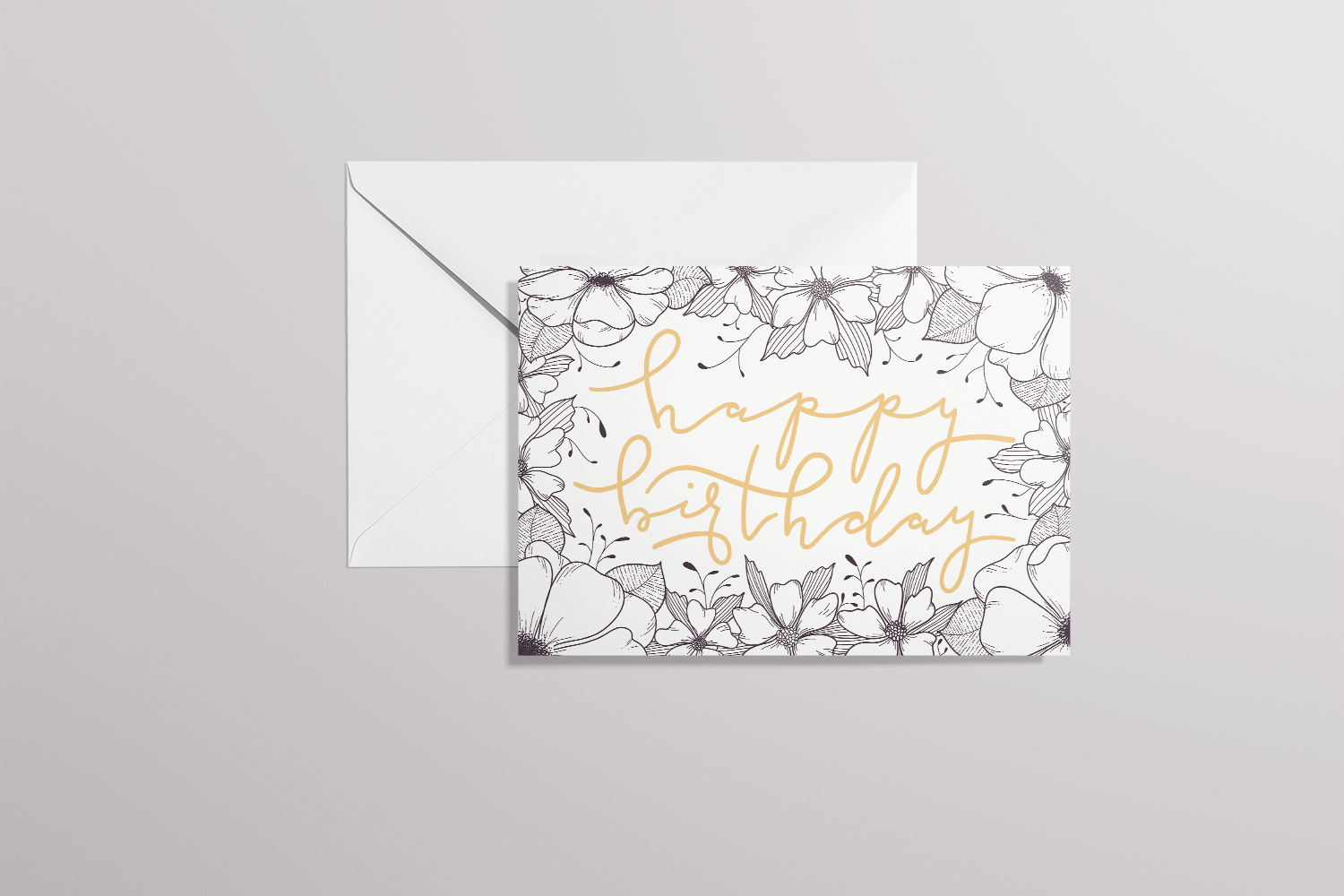 Mockup of card with floral border and a handwritten “happy birthday” in cursive on top of a white envelope