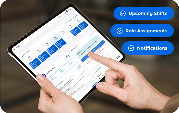 Person using a tablet displaying a digital work schedule with blue shift blocks, alongside icons labeled Upcoming Shifts, Role Assignments, and Notifications.