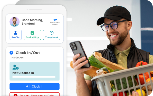 Smiling man wearing glasses and a black cap holding a phone and a shopping basket filled with groceries while viewing a clock-in app on his phone.