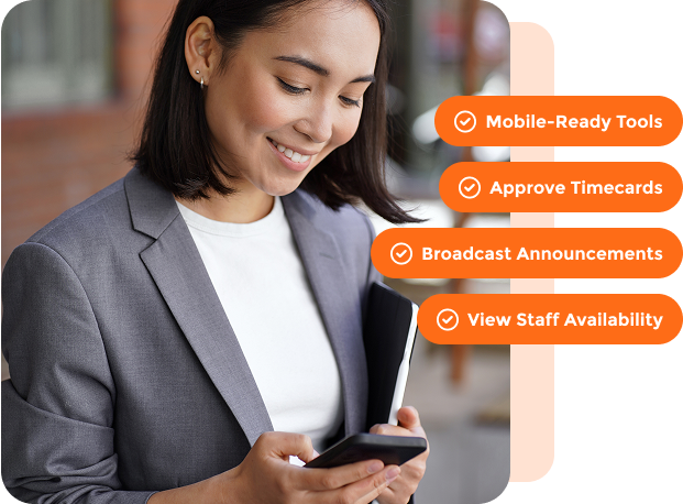 Smiling woman in gray blazer using smartphone with overlay text listing mobile-ready tools, approve timecards, broadcast announcements, and view staff availability.
