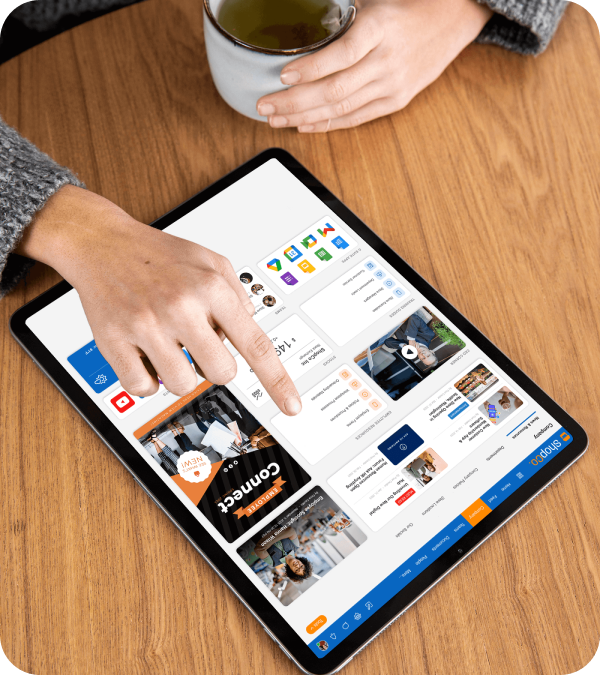 Person using a tablet on a wooden table, pointing at a messaging app interface with multiple chat and media windows, holding a cup of tea.