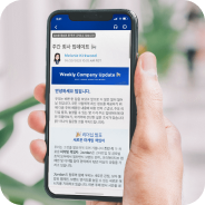 Hand holding a smartphone displaying a webpage with Korean text and blue header sections.