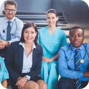 Group of diverse healthcare professionals, including doctors and nurses, smiling and sitting together.