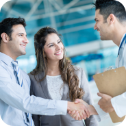 Two men shaking hands while a woman smiles between them in a professional setting.
