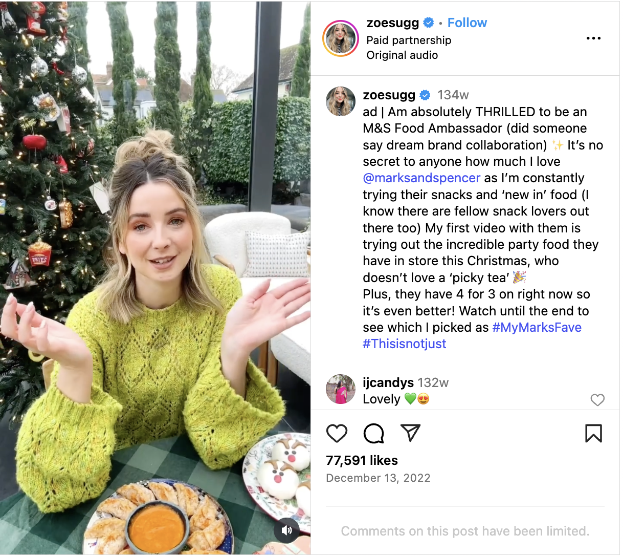 Zoe, dressed in a lime green sweater, sits at a table with Christmas snacks by Marks and Spencer  