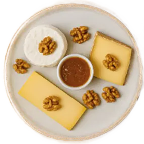 Plate with slices of cheese, walnuts, and a small bowl of brown sauce in the center.
