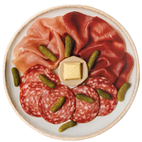 Plate with slices of different cured meats, small pickles, and a square piece of butter in the center.
