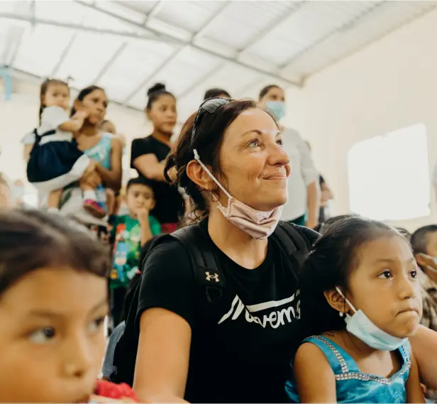 a person with a ponytail and a group of children in a room