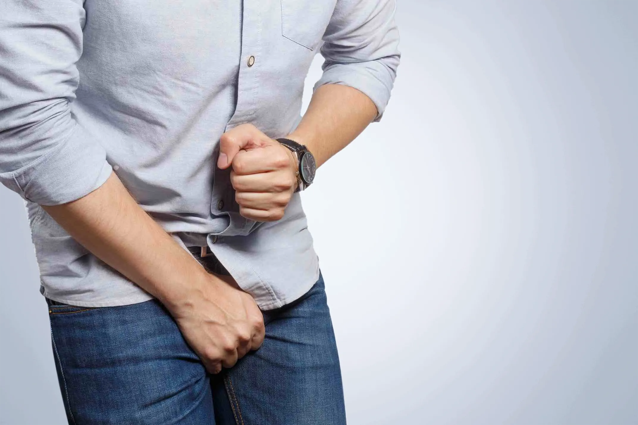 Mann hält sich den Unterleib wegen Schmerzen im Penis. | GoSpring