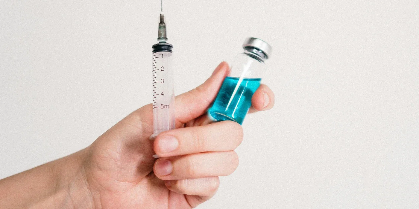 lprostadil-Injektion: Hand mit Spritze und Durchstechflasche mit blauer Flüssigkeit. | GoSpring