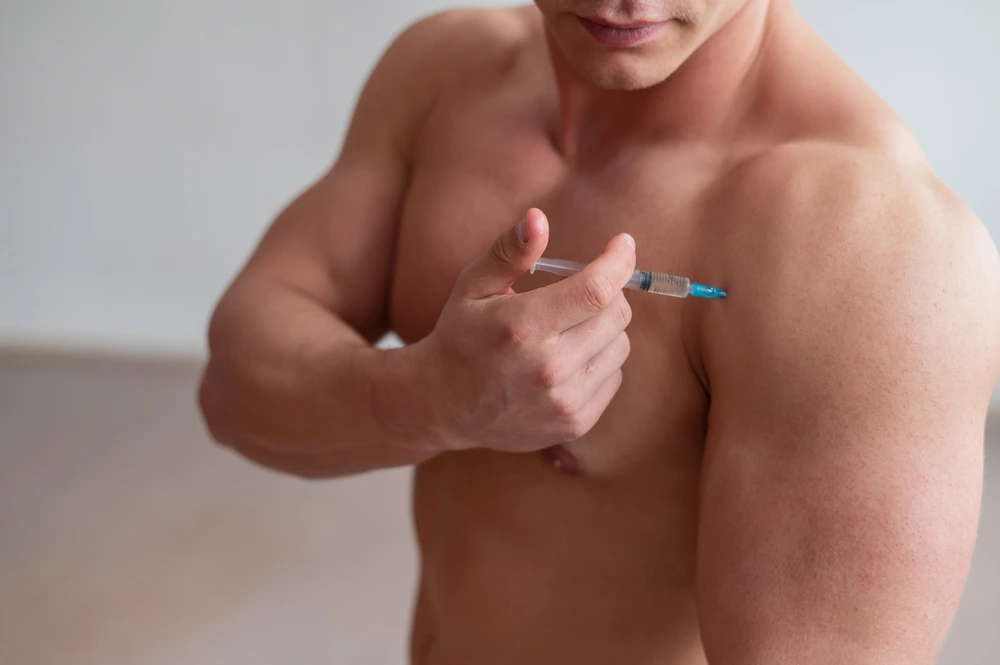 Mann spritzt Testosteron in den Oberarm – Testosterontherapie mit Injektion. | GoSpring