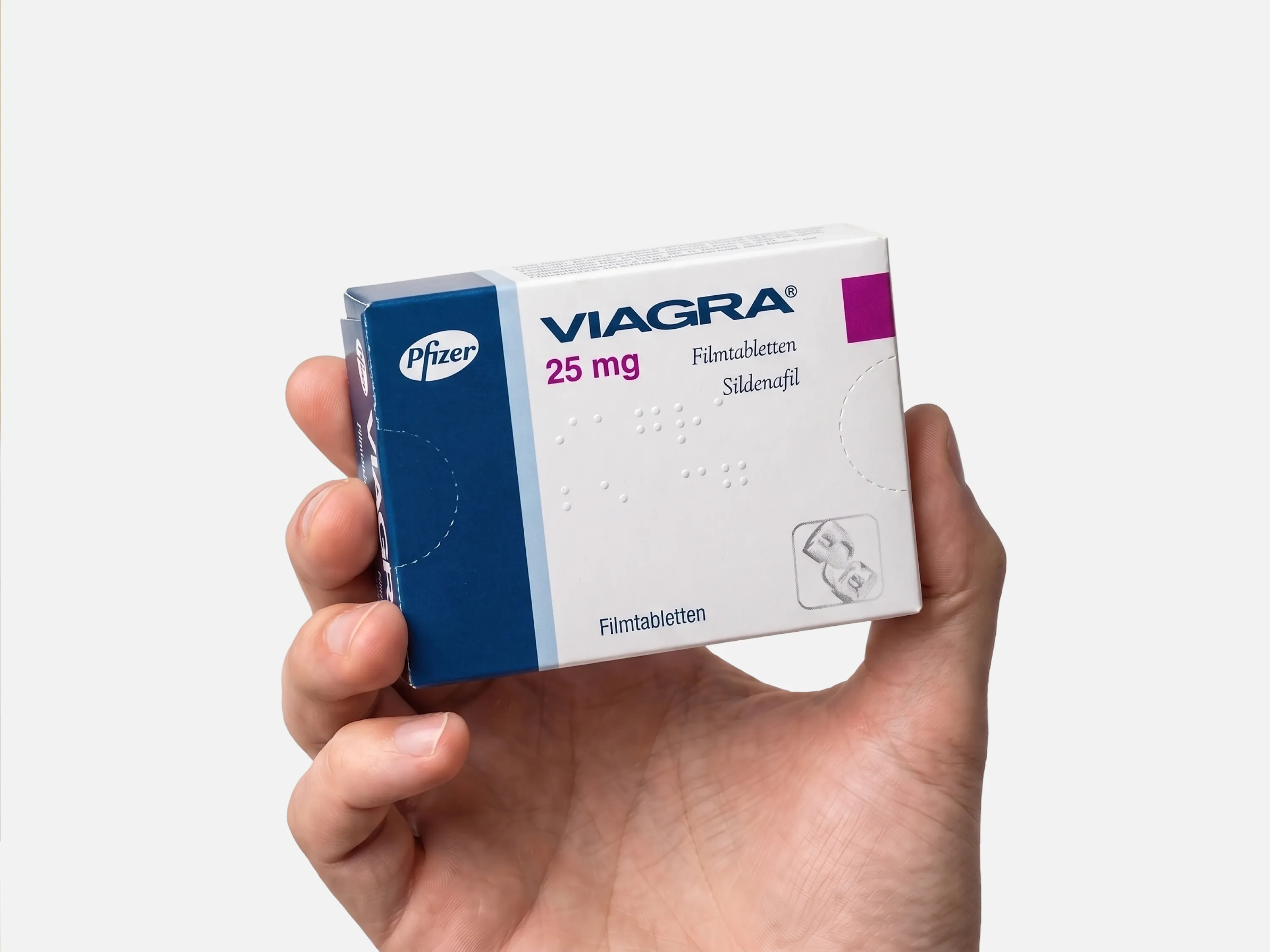 Viagra 25 mg Filmtabletten (Sildenafil) von Pfizer in einer Schachtel, in der Hand gehalten, vor weißem Hintergrund.