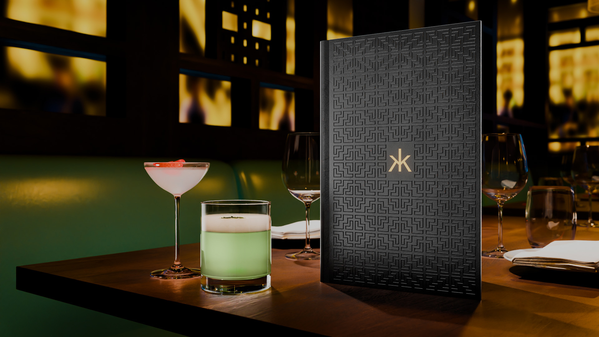 Bespoke cocktail menu designed by Knockout for Hakkasan, displayed beside cocktails, with a black lattice-patterned cover echoing the restaurant’s wooden screens and a gold Hakkasan logo.