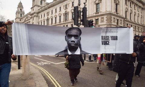 Protesters holding banner with image of Marcus