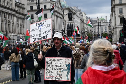 A man holds a sign criticising Israel and the Unite the Kingdom rally.