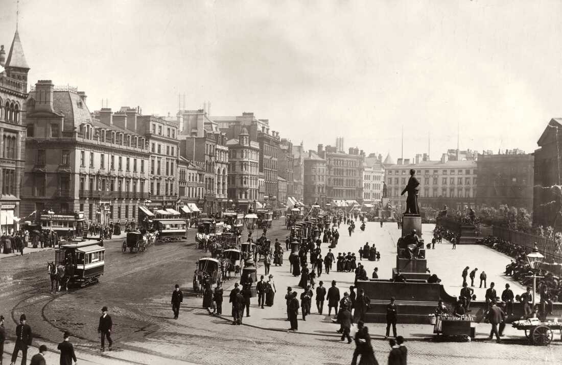 People and horse-drawn carriages are seen in Manchester circa 1880.