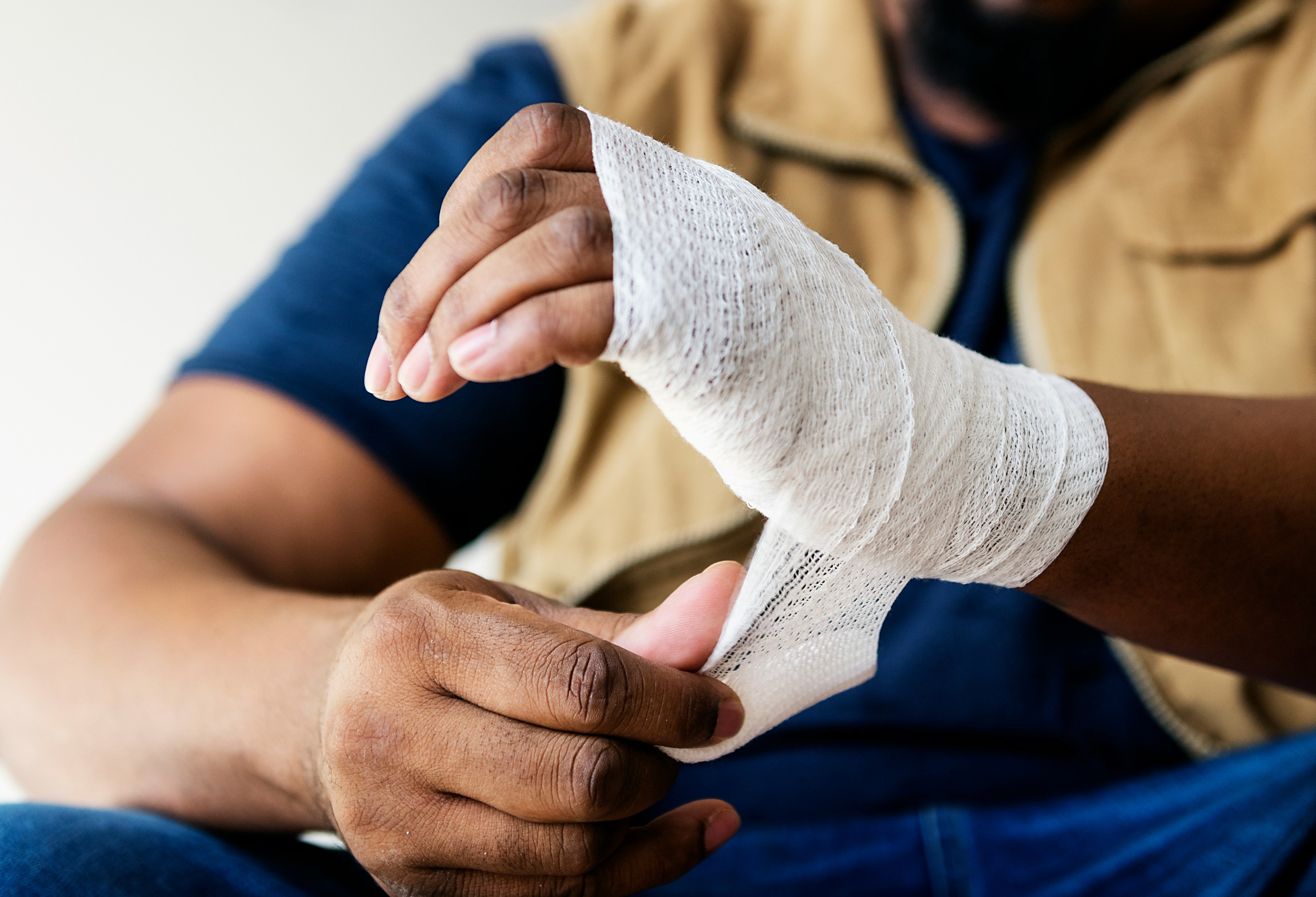 Person's left hand being wrapped with a cloth bandage.
