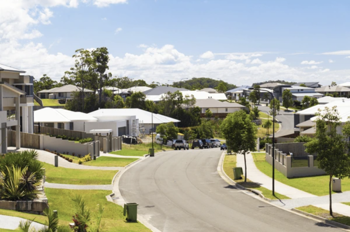 Modern Australian suburban street with contemporary houses, green lawns, and blue sky on a sunny day