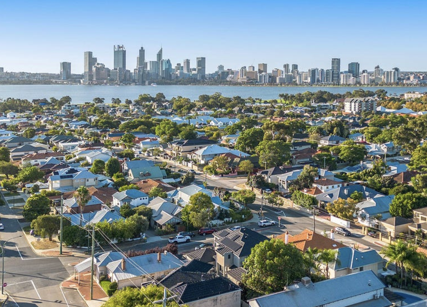 Aerial view of Perth residential suburbs showing diverse housing types with Perth CBD skyline and Swan River in background, illustrating Australian property market growth and urban development trends.
