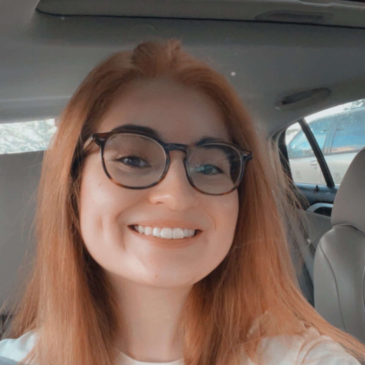 The artist, Isabella, smiling at the camera in her car
