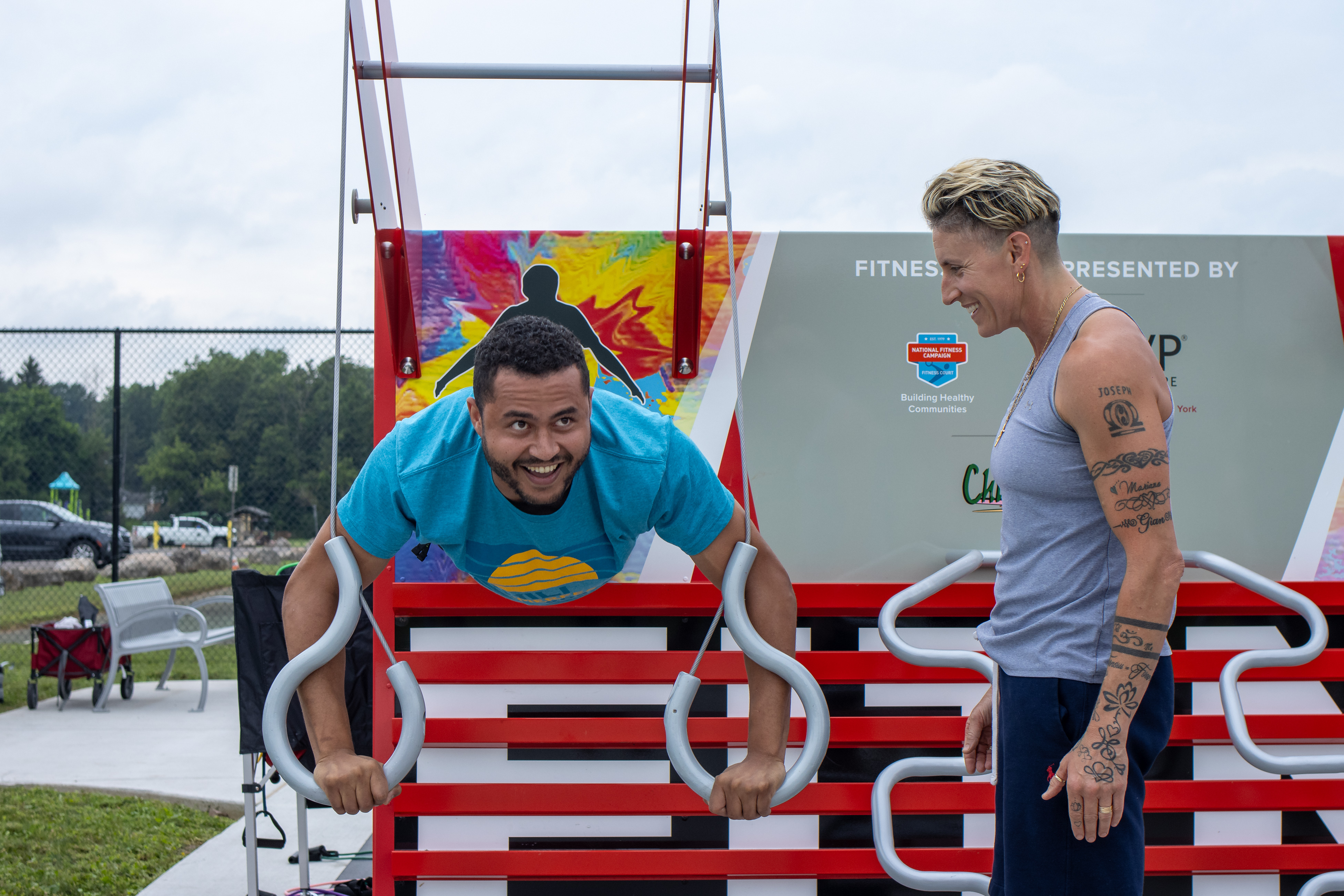 Two community members using the rings on a Fitness Court outdoors