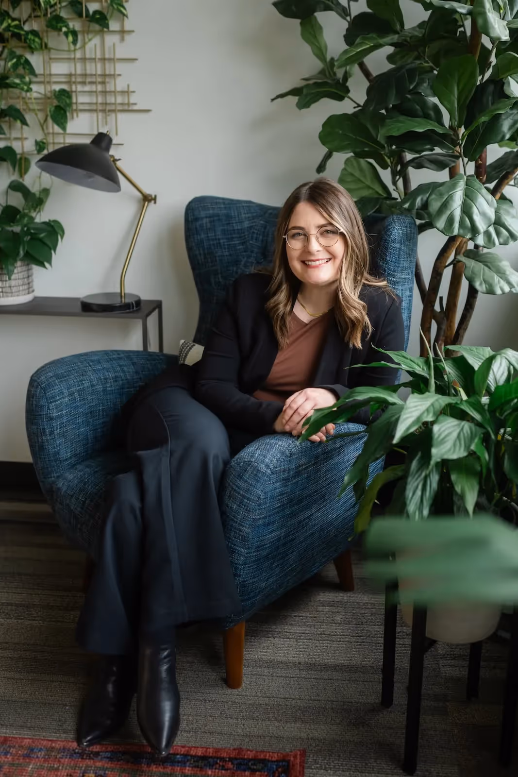 Dr. Carly Claney sitting in a chair smiling at the camera with her head resting on her hand