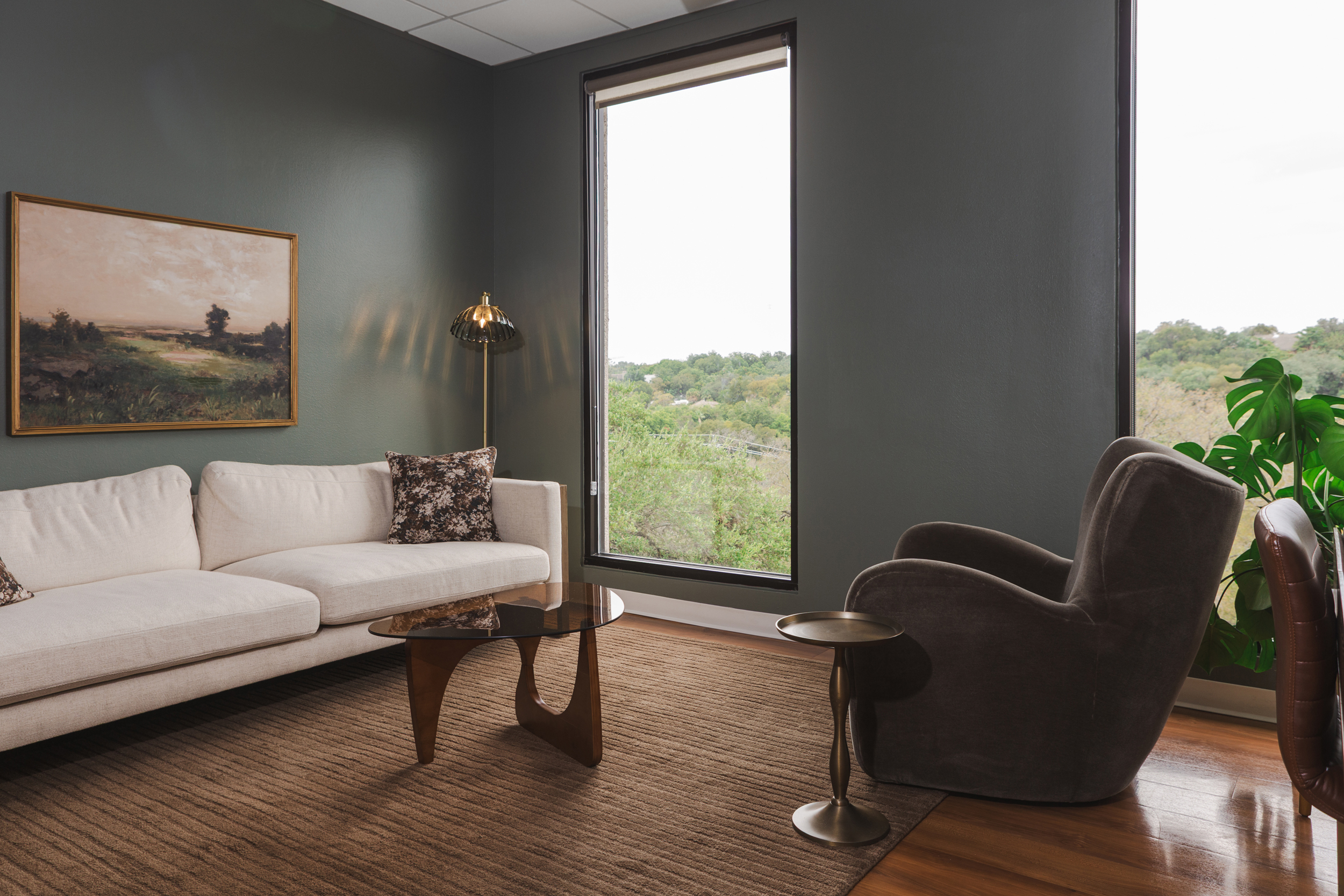 Therapy office at Decades Counseling with a cream sofa, grey armchair, and a window looking onto trees