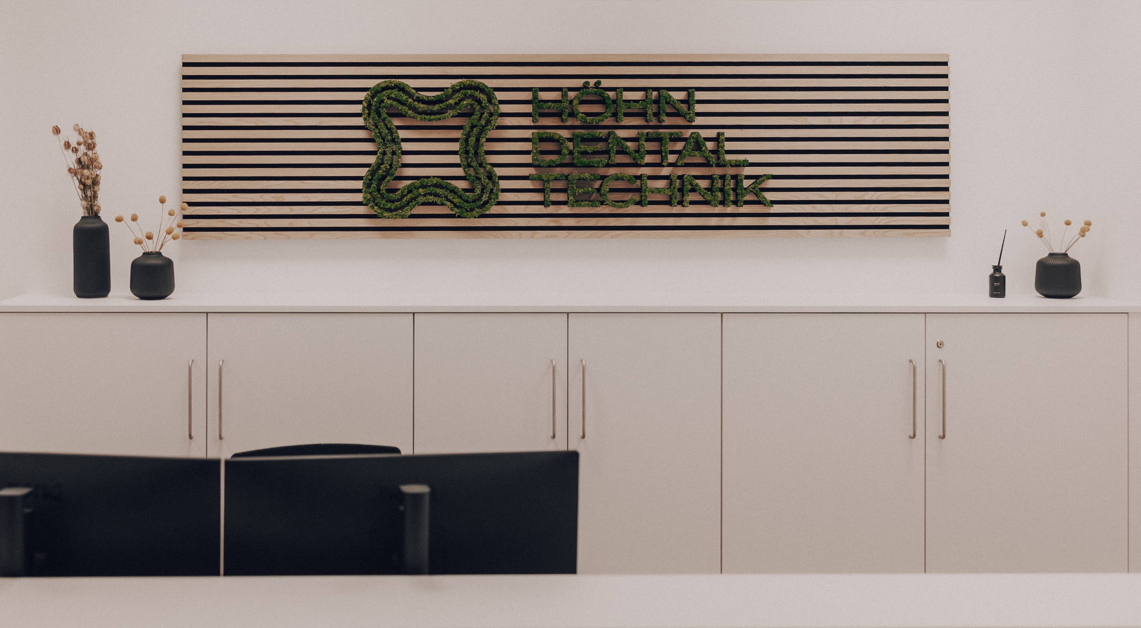 Höhn Dentaltechnik Empfangsbereich – Mooswand-Logo aus Naturmoos an Holzlamellen-Wandpaneel