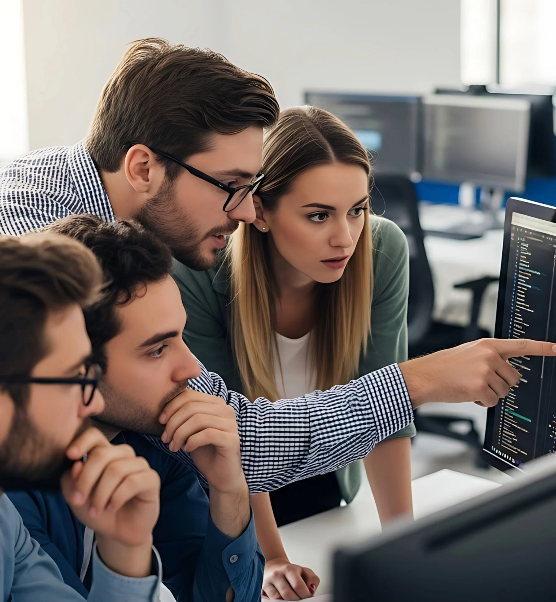 Four colleagues looking at code on a monitor in an office