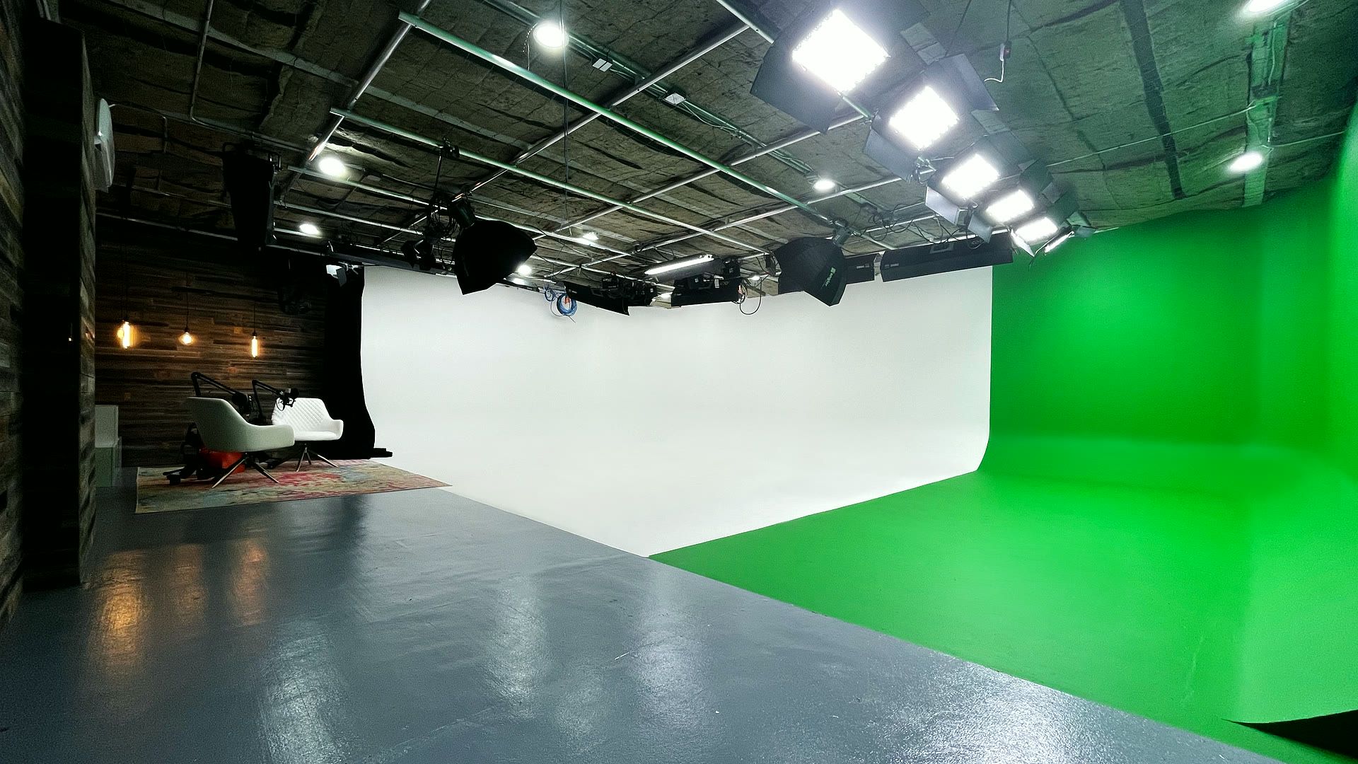 Studio A white cyc and green screen cyc meeting in a corner under a ceiling lighting grid.