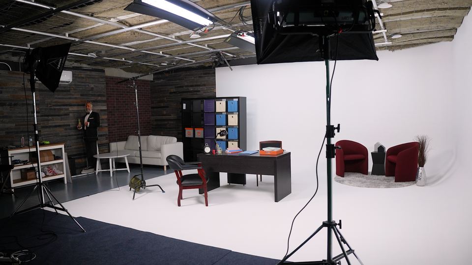 Studio A in Coconut Grove, Miami, with an office set of a desk and red armchairs on the white cyc under studio lights.