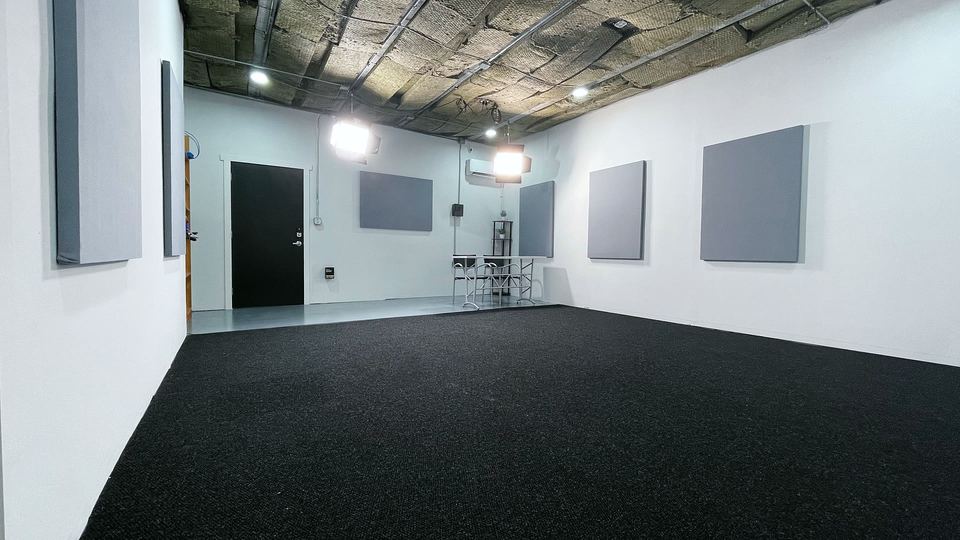 Reverse view of Studio B showing the black carpet floor, grey panels on white walls and the entrance door.