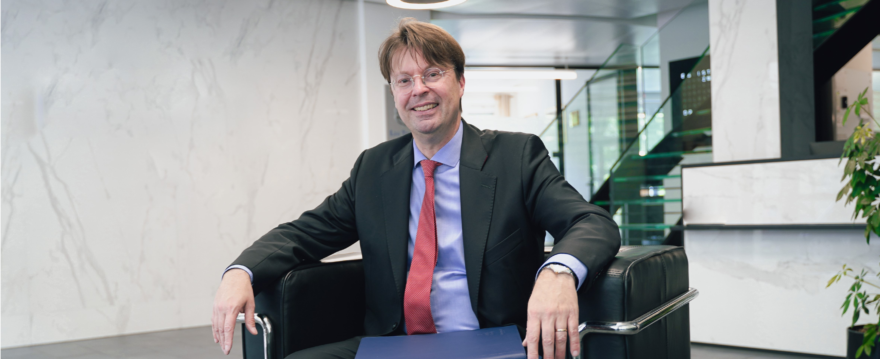 Man in a suit seated in a chair in a modern office