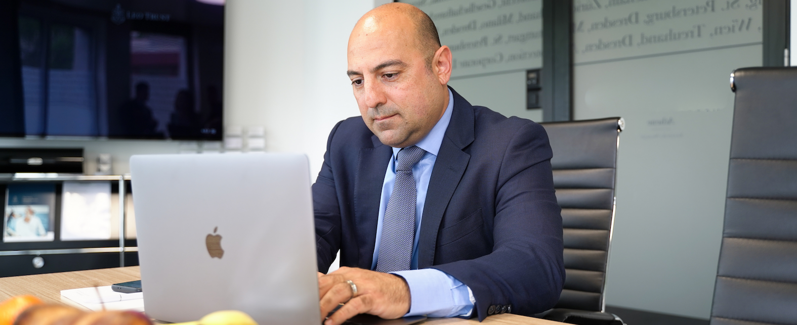 Managing Director of Leo Trust Cyprus at his desk with a laptop