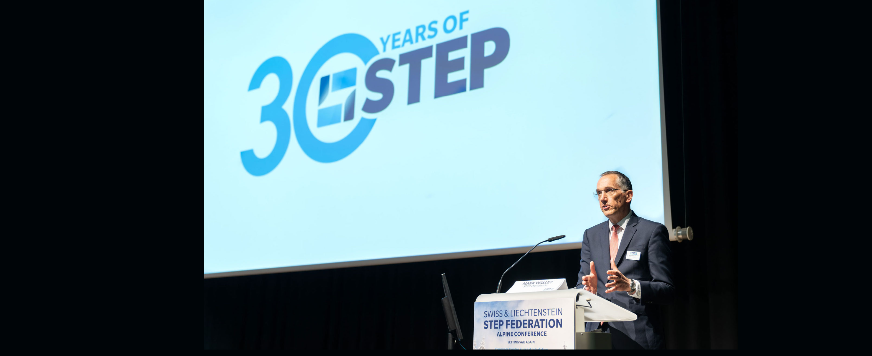 Speaker at a lectern in front of a screen reading 30 Years of STEP