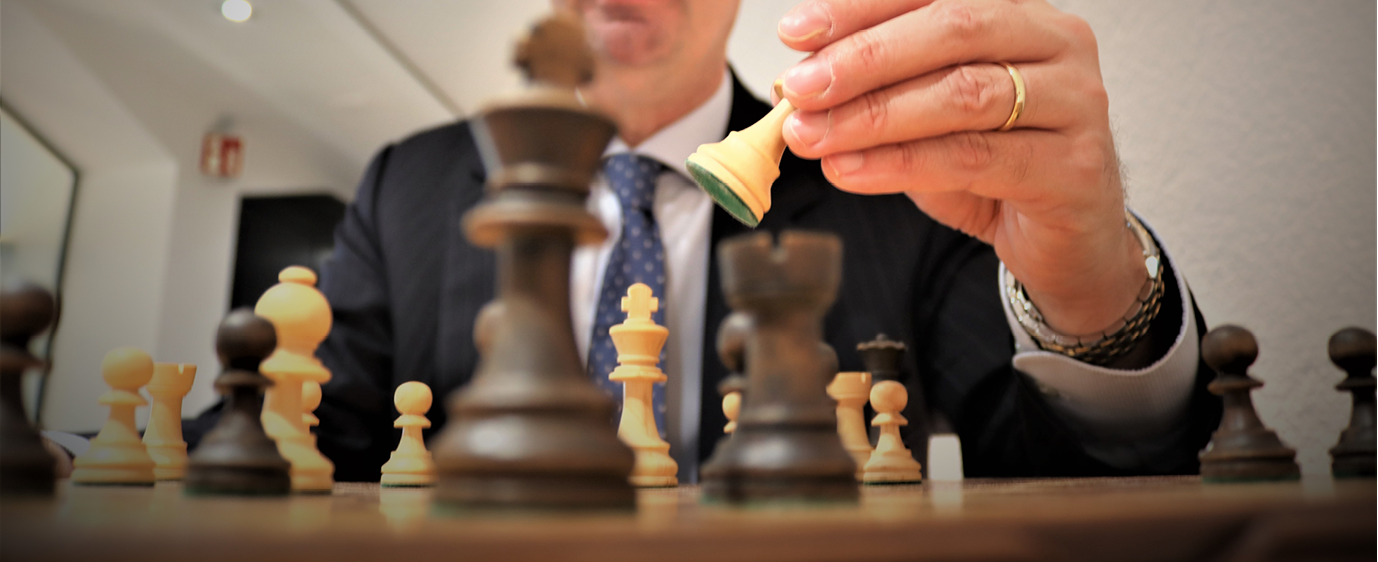 Hand in a suit sleeve placing a chess piece on a board
