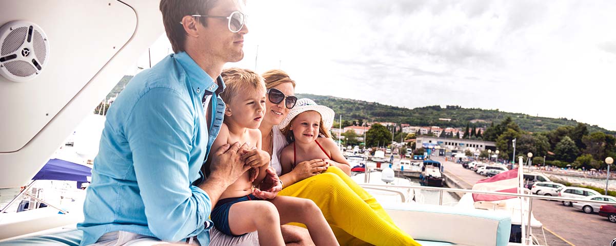 Family with two children sitting on grass overlooking a marina