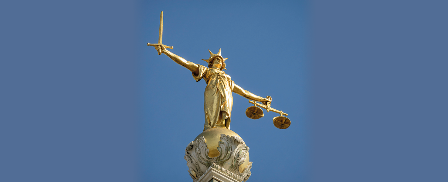 Golden statue of Lady Justice with sword and scales against a blue sky