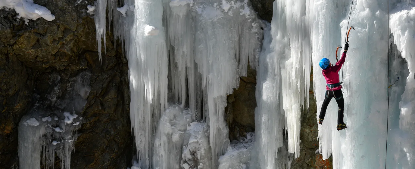 Climber on a frozen waterfall of blue ice
