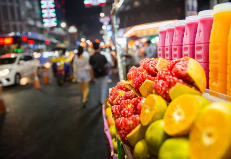 A road side stall displaying local fruits like pomegranate and oranges with freshly pressed colorful fruit juices.