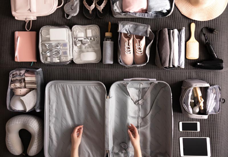 a flat lay of essential travel items arranged in traveling cubes before being packed in a medium-sized luggage bag..