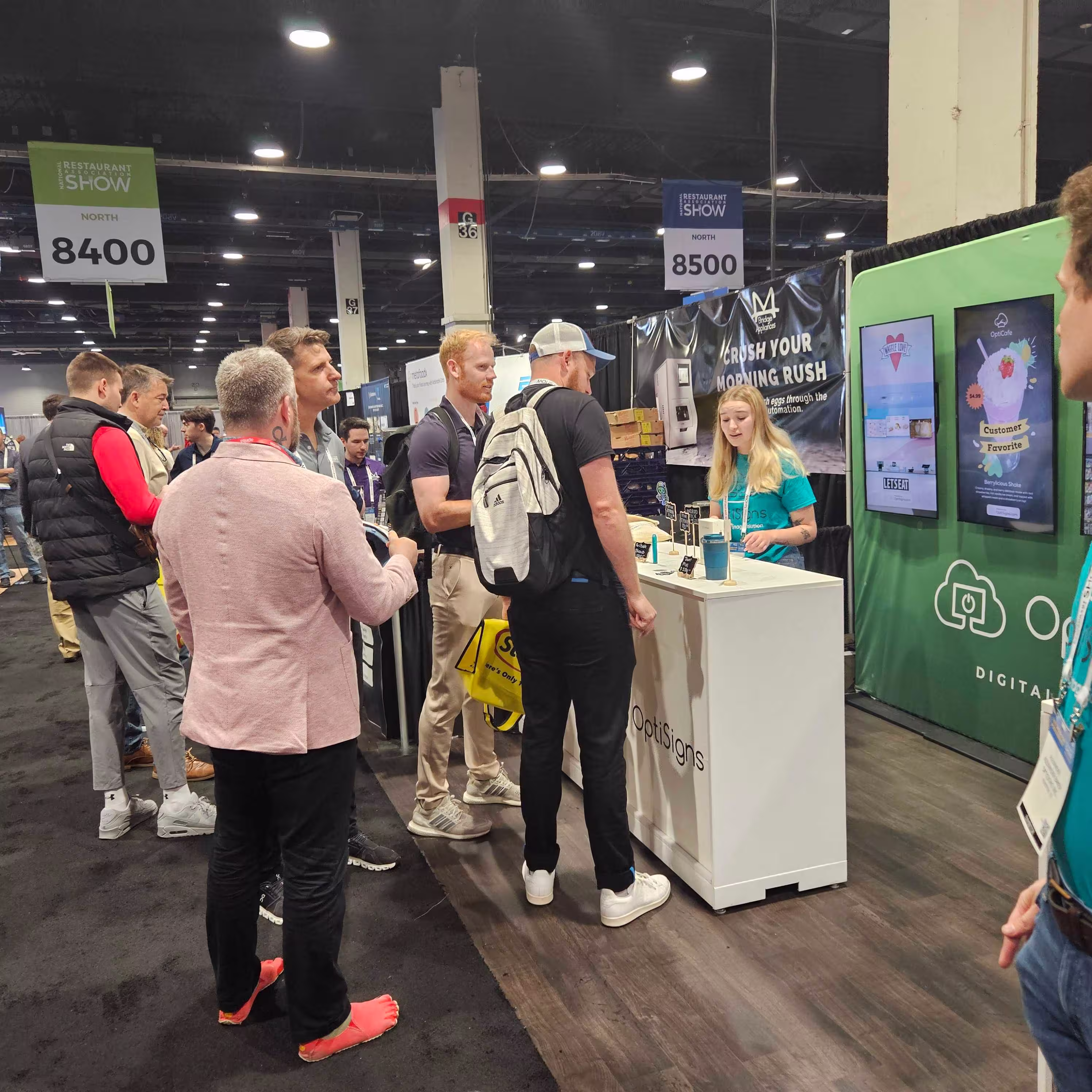 OptiSigns employee talking to a crowd of people at a tradeshow.