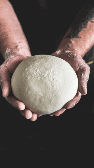 A gif of a pair of hands holding pizza dough being added to a design.