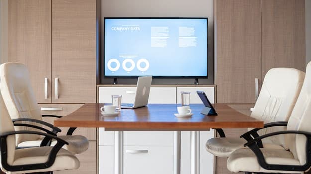 A digital signage screen portraying company data in a meeting room.