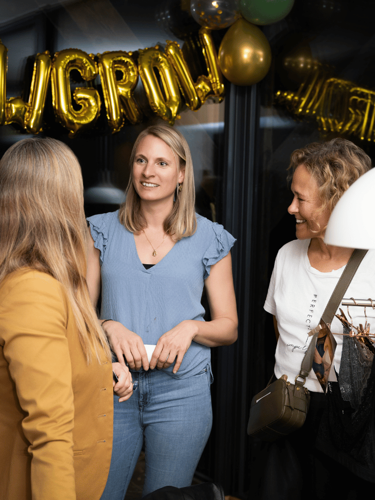 Drei Frauen unterhalten sich, im Hintergrund die goldenen Glow Grow Luftballons.