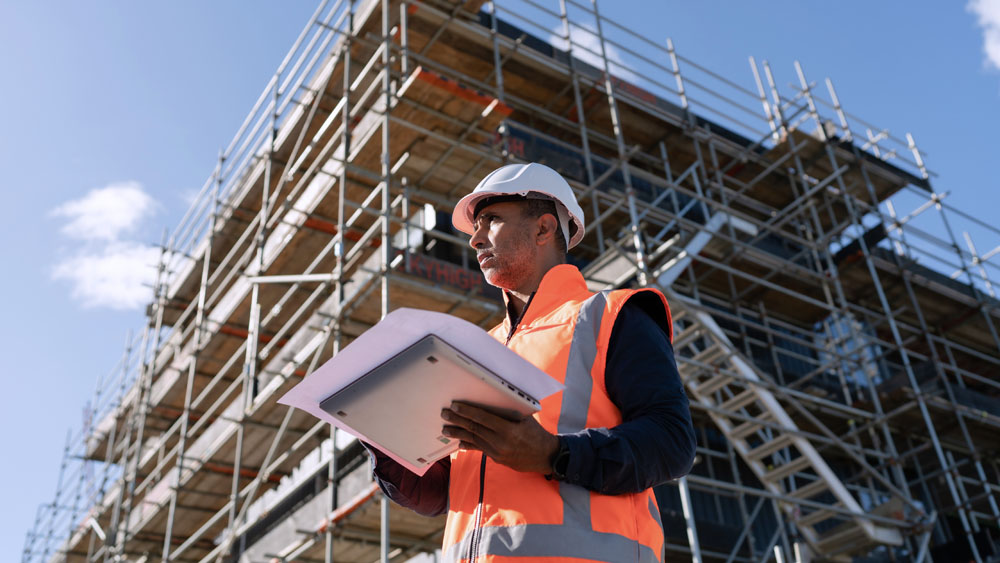 A construction worker standing in front of a building under construction.