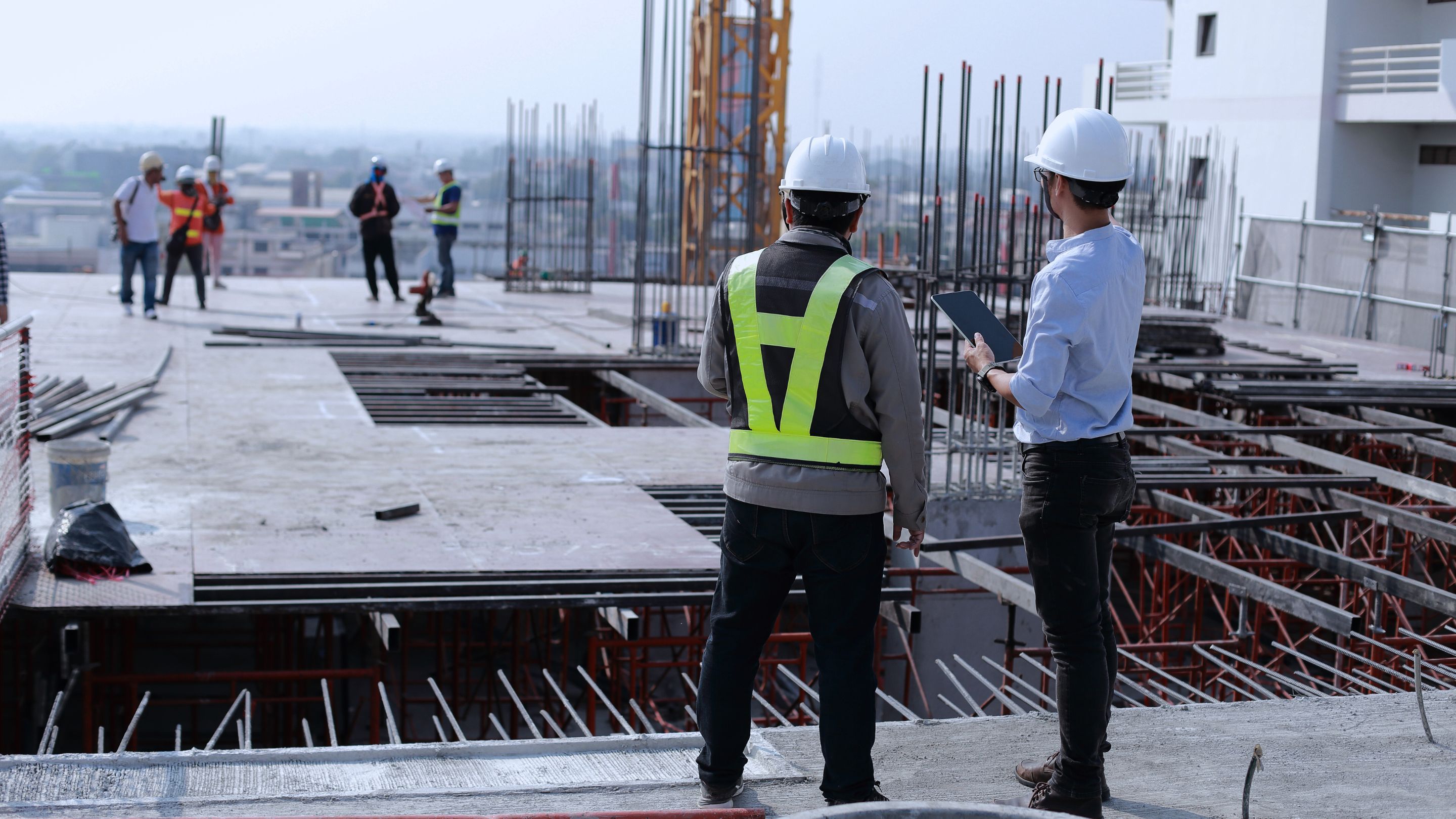 A couple of men standing on top of a building under construction.