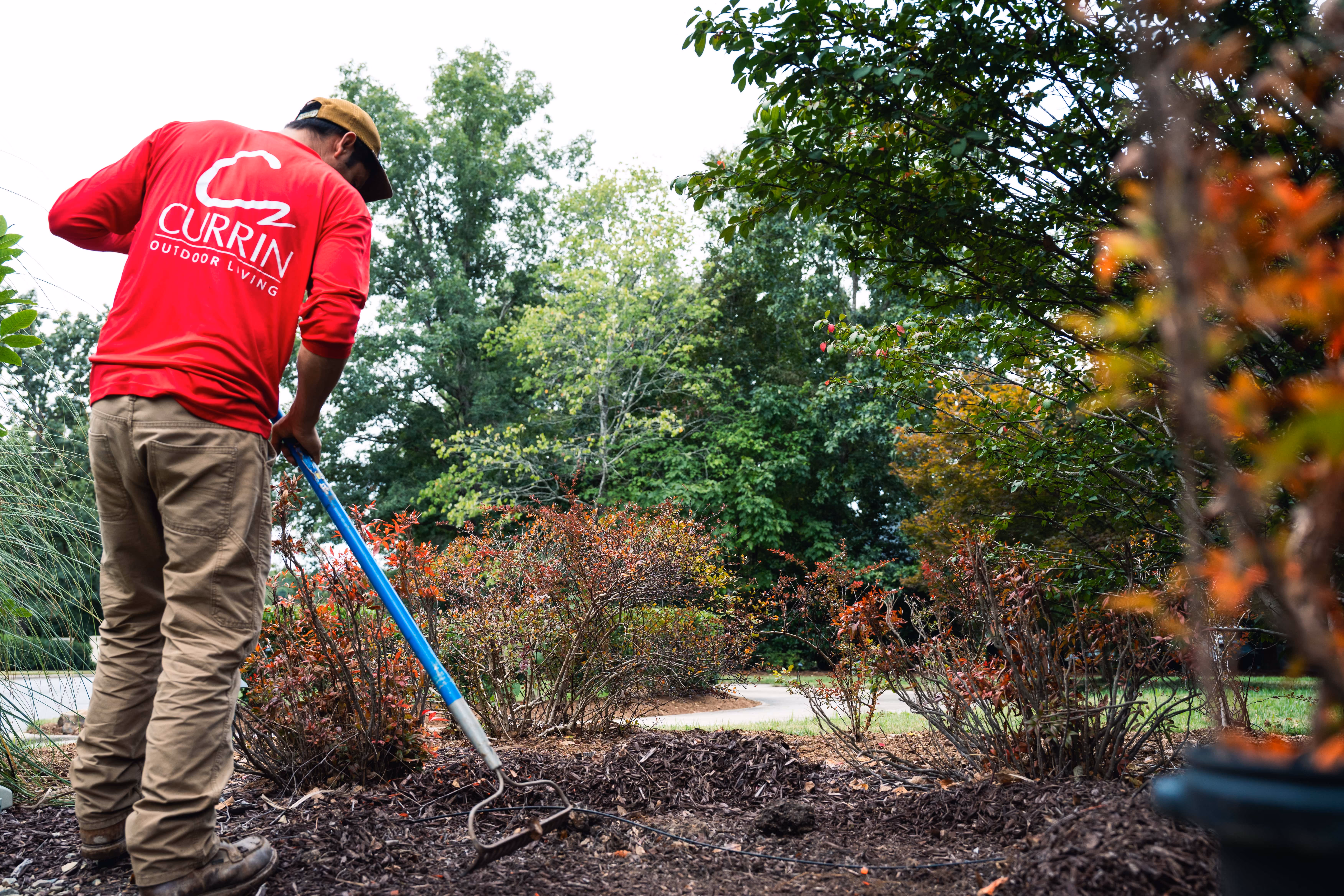 Currin Outdoor Living team member installing premium landscape design bedding for a luxury backyard project in Raleigh, NC.