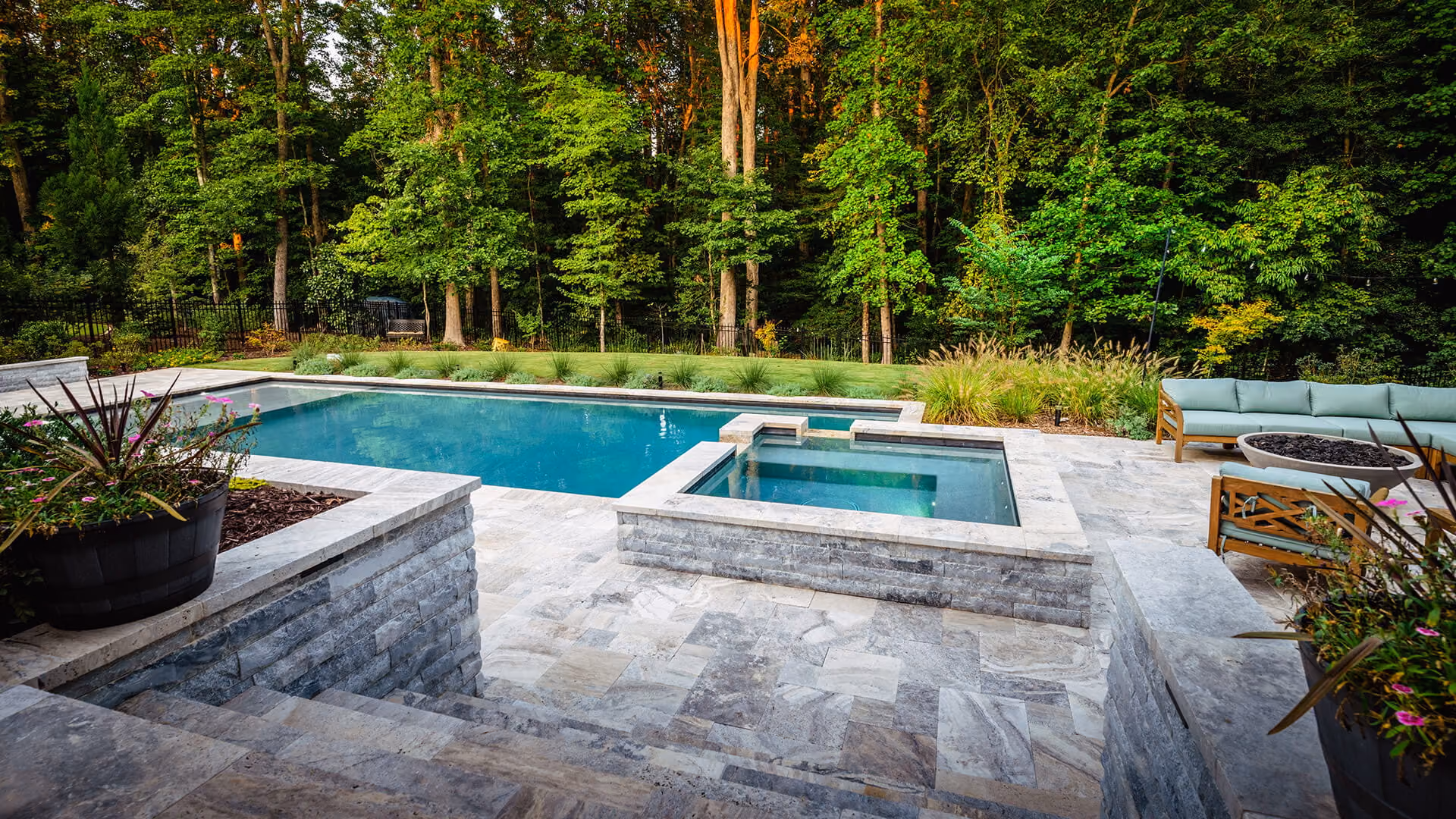 An aerial perspective of a premium residential backyard transformation in Raleigh, NC, featuring a custom inground swimming pool, stone patio lounge, and elegant landscaping design by Currin Outdoor Living.
